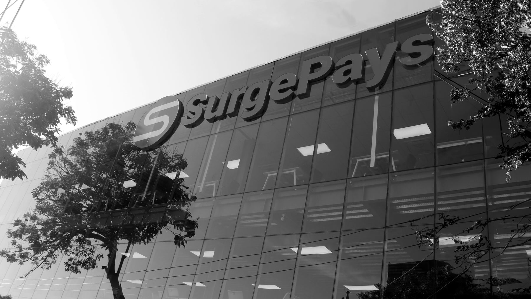 The SurgePays operations center in El Salvador, a glass building with the SurgePays sign